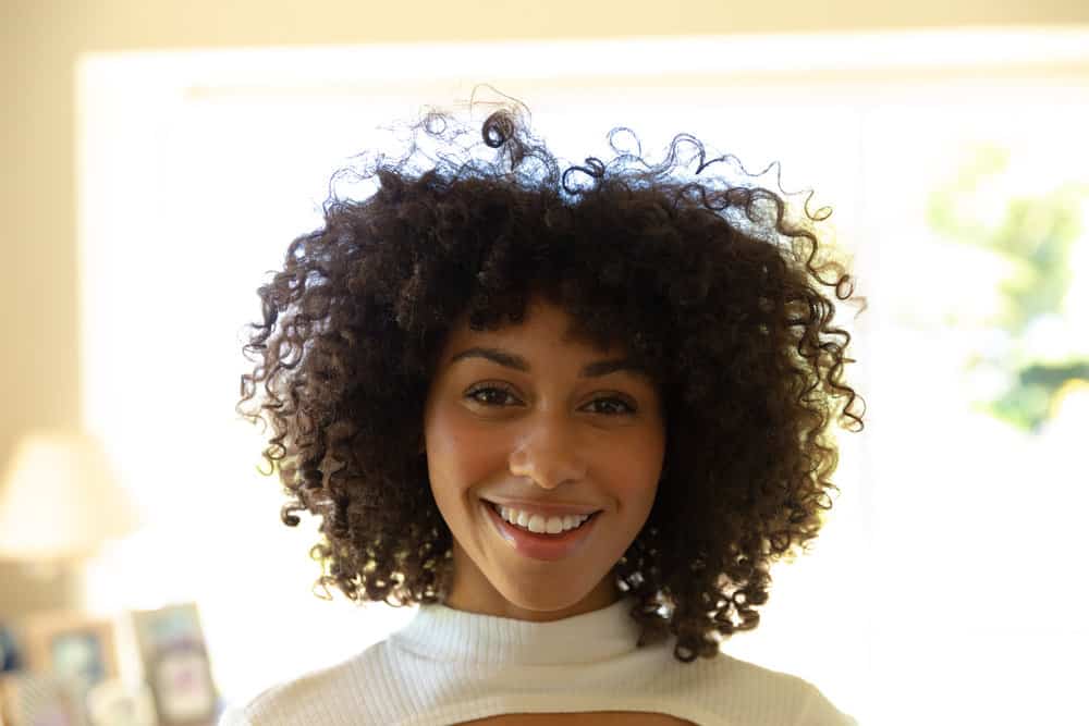 Cute young African American female with healthy hair styled with camphor and coconut oil to treat a flaky scalp.