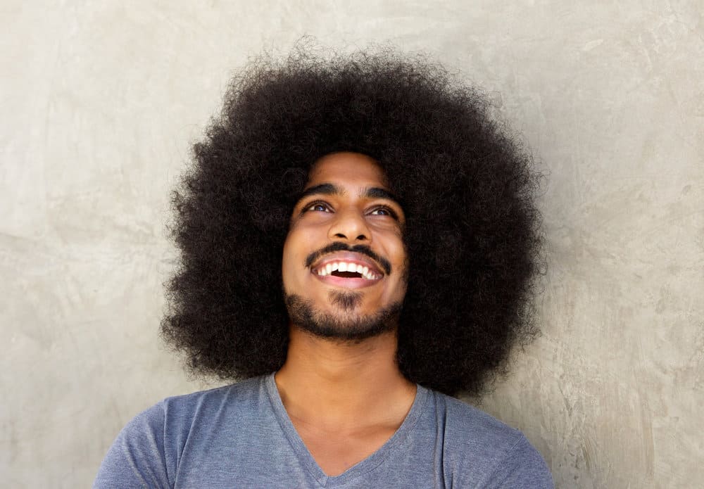 A guy with a big curly hair and his hair down after not getting a haircut for several years.