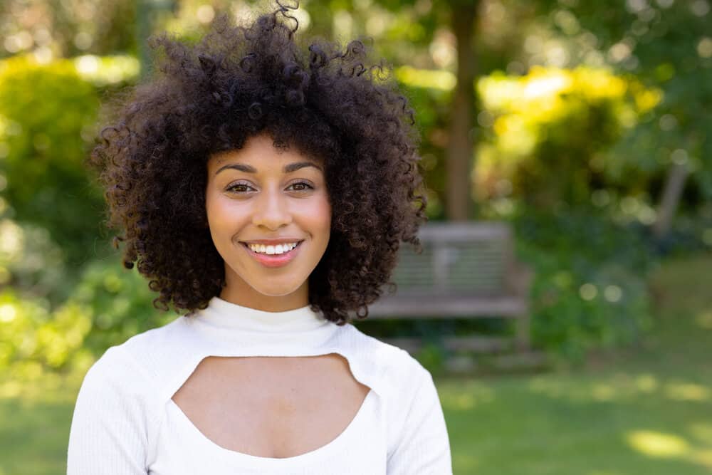 African American woman with type 4 natural hair wearing a white sweater.
