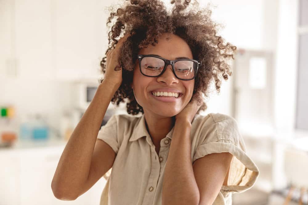 African American female with towel-dried hair enjoying her natural curls after using Olaplex shampoo and conditioner.