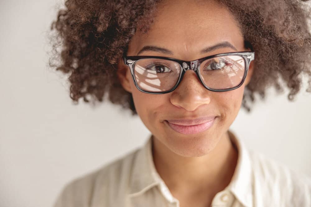 Young African American female with healthy hair growth after suffering from thin hair due to excessive heat styling.