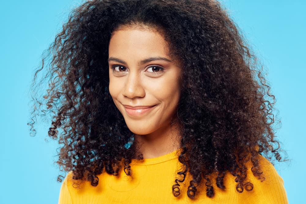 Cute young black girl with curly hair follicles that suffered from female pattern hair loss and hair thinning.