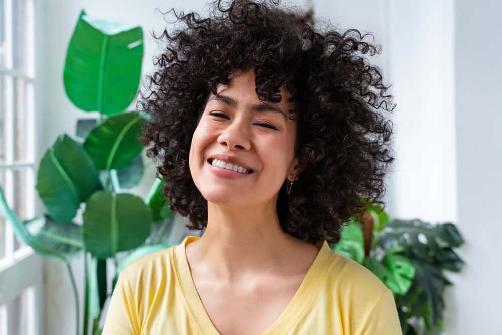 A beautiful Latino female with naturally frizzy hair has beautiful curls after using an uncooked rice water rinse.