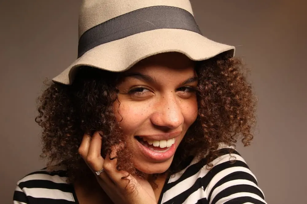 Does Wearing a Hat Cause Dandruff? Baseball cap? Everyday? 1 Cute black girl wearing a stylish hat to keep her ears warm but it's causing an irritated scalp and making dandruff.