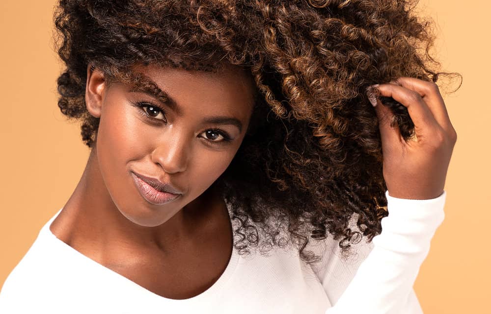 A lady wearing dark brown and black dyed curls covering her forehead with the bouncy curly layers.