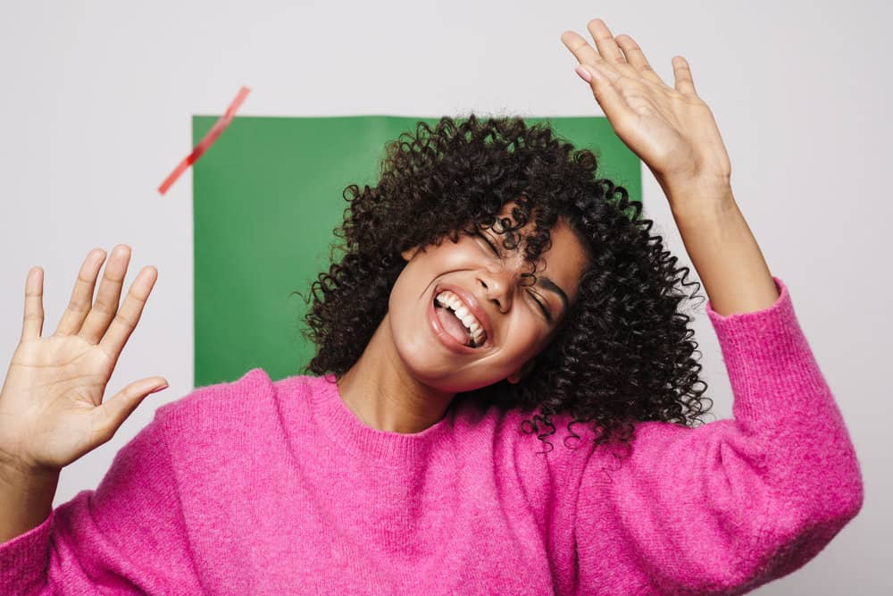 A black woman with curly hair follicles and too little moisture has an itchy scalp and minor dandruff.