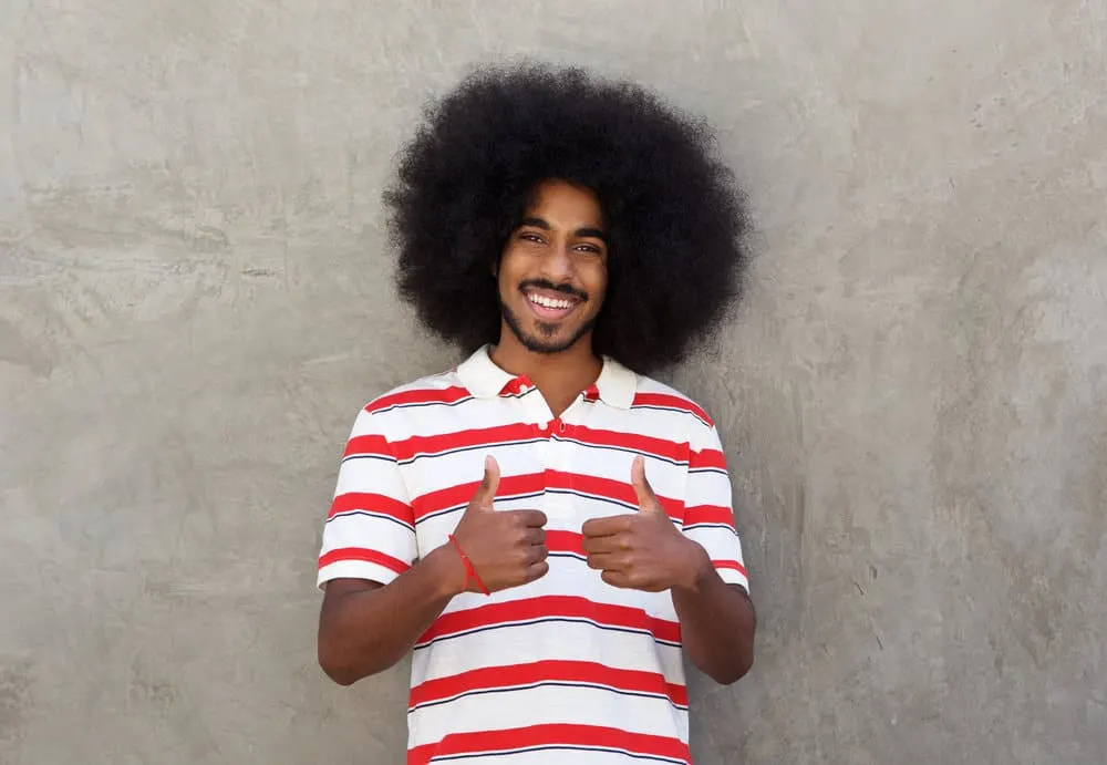 What Long Hair Says About a Man? What Does It Symbolize? 3 A young man with both thumbs up wearing his hair long after not getting a hair cut for several years.