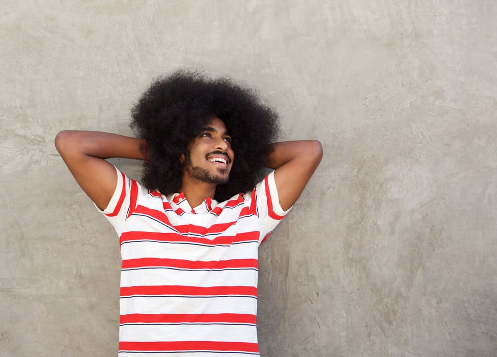 Young African American male with hands behind head with a 4B hair type.