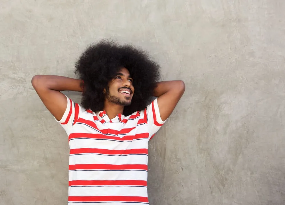 What Long Hair Says About a Man? What Does It Symbolize? 6 Young African American male with hands behind head with a 4B hair type.