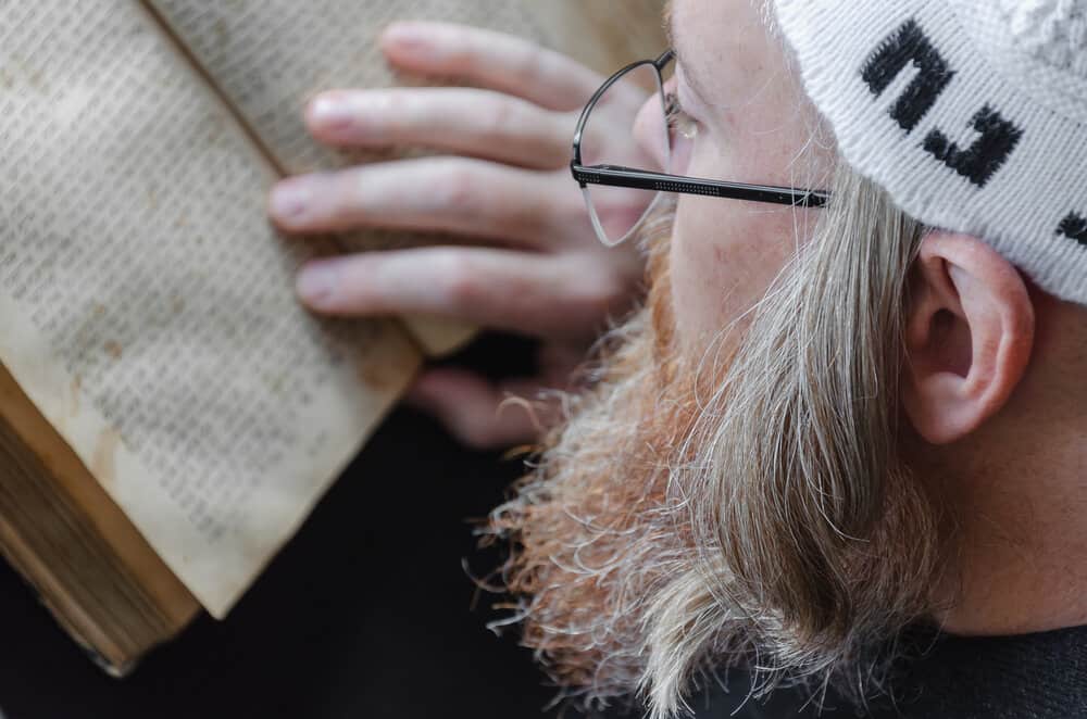 Hasidic Jews, like this man with curly hair, read the Siddur according to the Jewish religion.