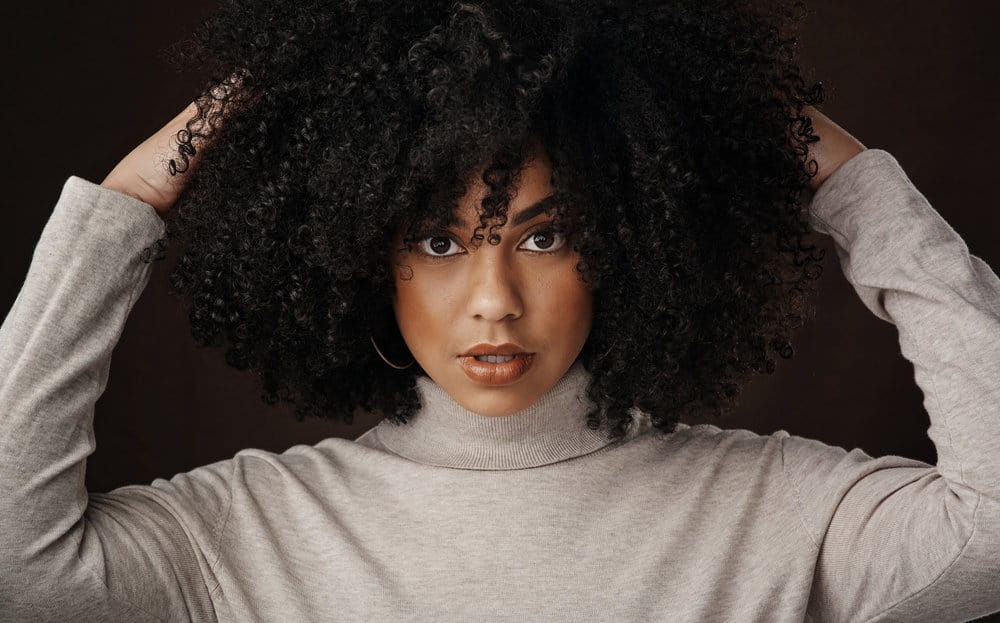 Cute African American woman with clean hair styled with a round brush head and a wide-tooth comb.