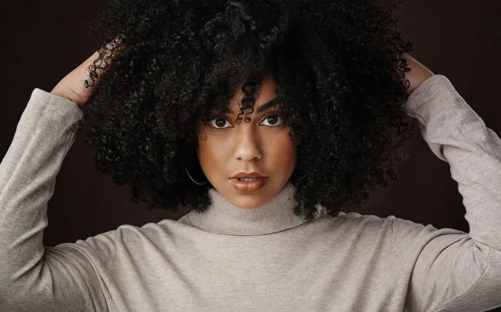 How Do You Clean Lint Out of a Hairbrush: Step-by-Step Guide 1 Cute African American woman wearing loose hair with a round brush head and a wide-tooth comb.