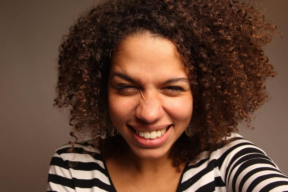 African American female wearing semi-permanent hair dye on her medium brown natural curls.