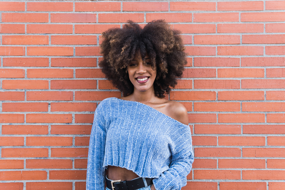 Positive lady with a great smile with stiff hair strands from using too much protein on her medium porosity curls.