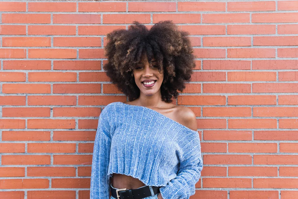 Positive lady with a great smile with stiff hair strands from using too much protein on her medium porosity curls.