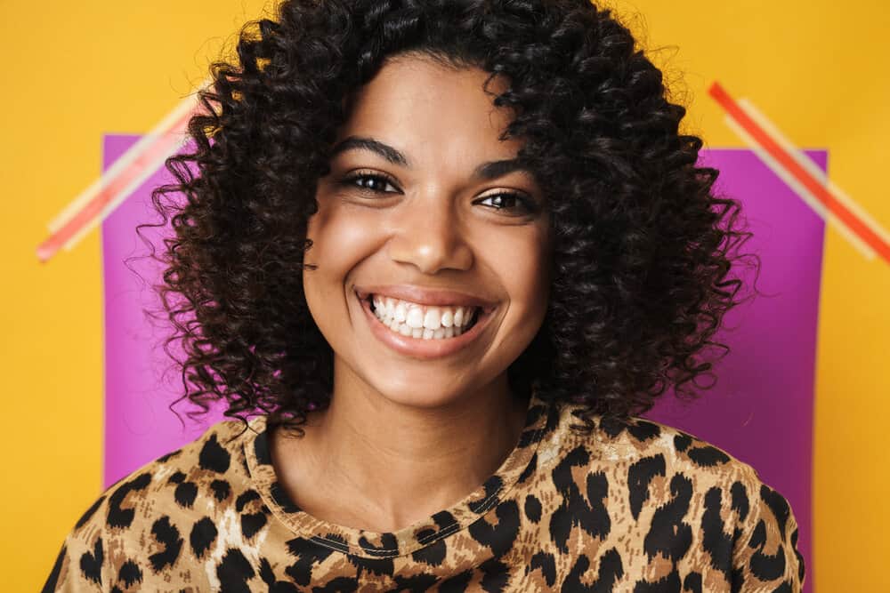 Cute young African American female with color-treated hair suffering from an itchy scalp due to dandruff.