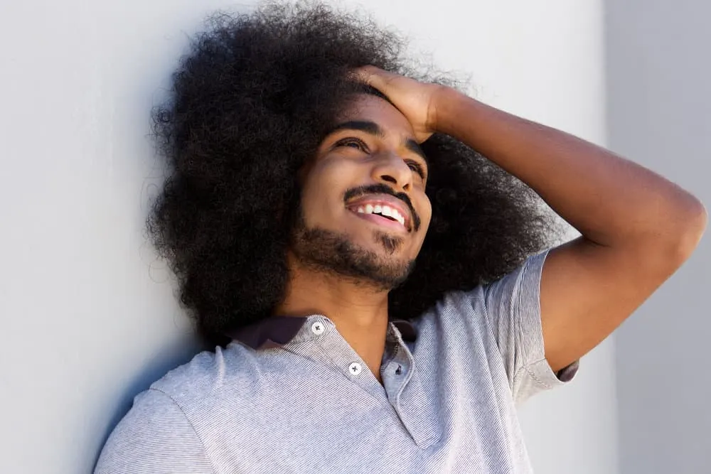 What Long Hair Says About a Man? What Does It Symbolize? 9 Young man laughing after considering his cultural identity after growing long hair affected his self-esteem.
