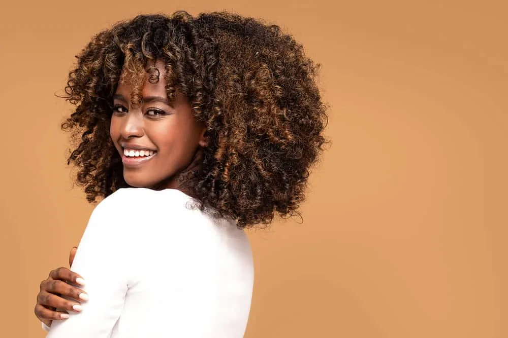 What Are Bottleneck Bangs? How to Cut and Style DIY Bangs 5 Beautiful African American woman wearing a trending haircut with long bangs that are bottleneck shape.
