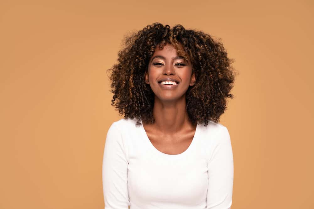 Cute dark-skin black girl with a 3B hair type embracing the fringe trend wearing heavily layered longer bangs.