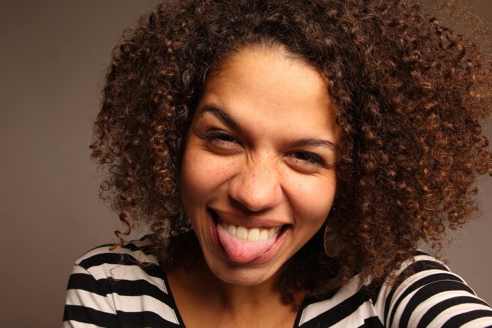 A black woman with medium brown natural hair, wearing semi-permanent hair color on her locks.