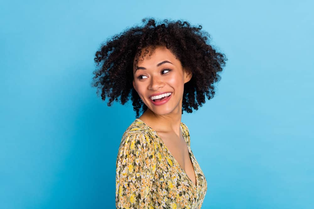 A charming lady with damp hair after washing her curls and styling them with a wide-tooth comb.