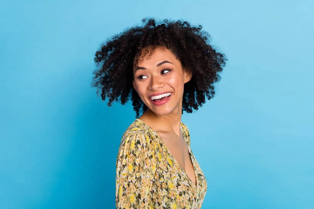 Why Is My Hair Crunchy When It Dries (and at the Ends)? 3 A charming lady with damp hair after washing her curls and styling them with a wide-tooth comb.