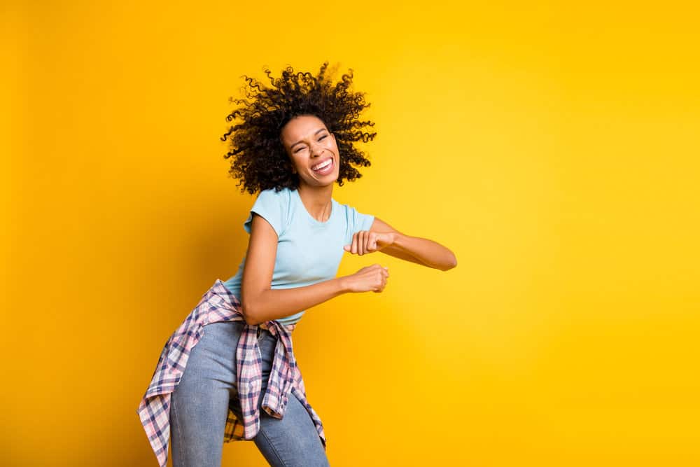 A young African girl with medium-brown hair color on her 3B curls after using bleaching powder.