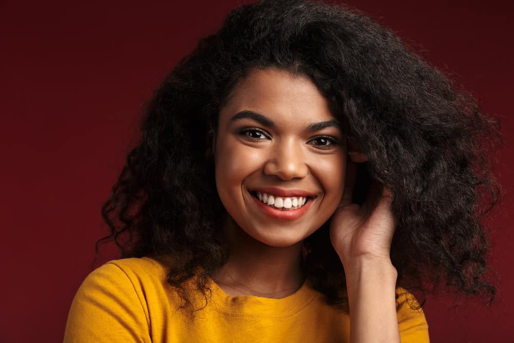 African American lady decided to straighten hair with coconut oil to keep her curly hair healthy.