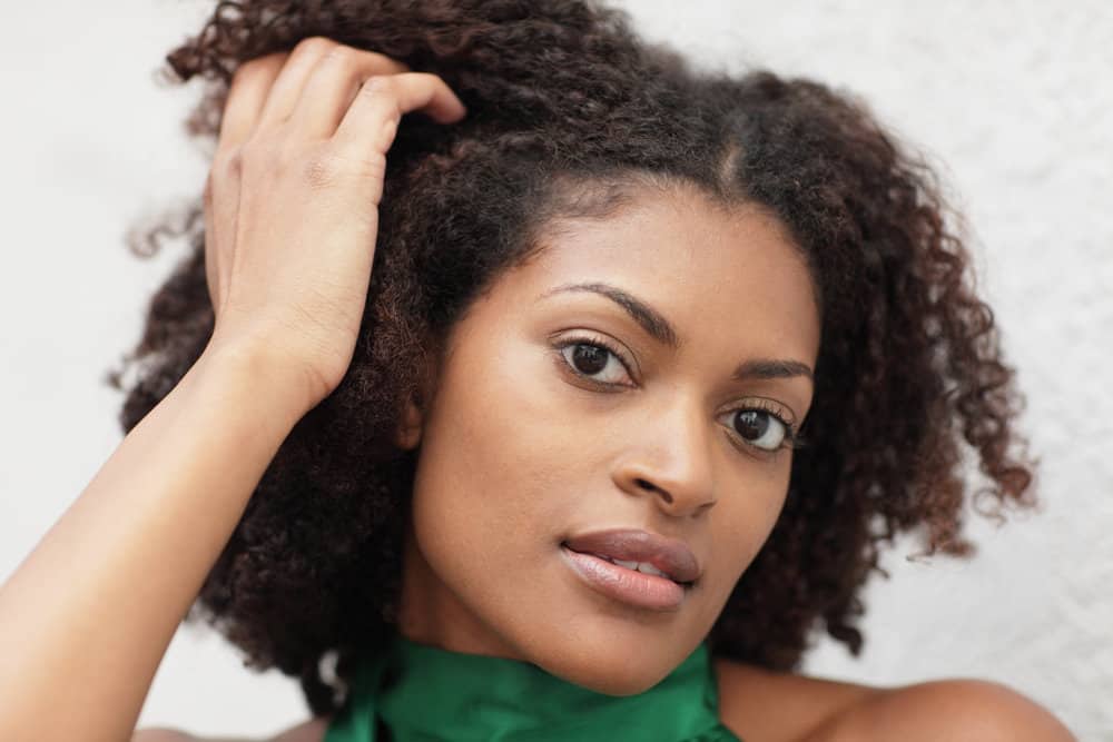 Cute young African American female with 4A curls admiring her hair health and reduced breakage from a healthy diet.