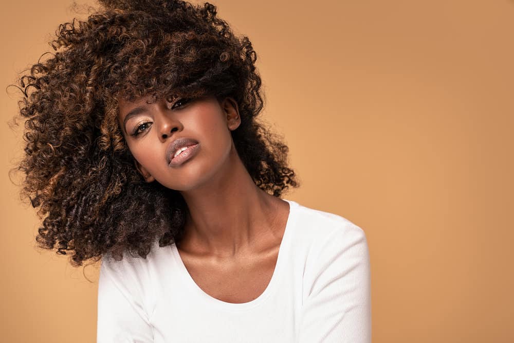 Beautiful young African American woman with natural curls covering her brow bone at the cutting line.