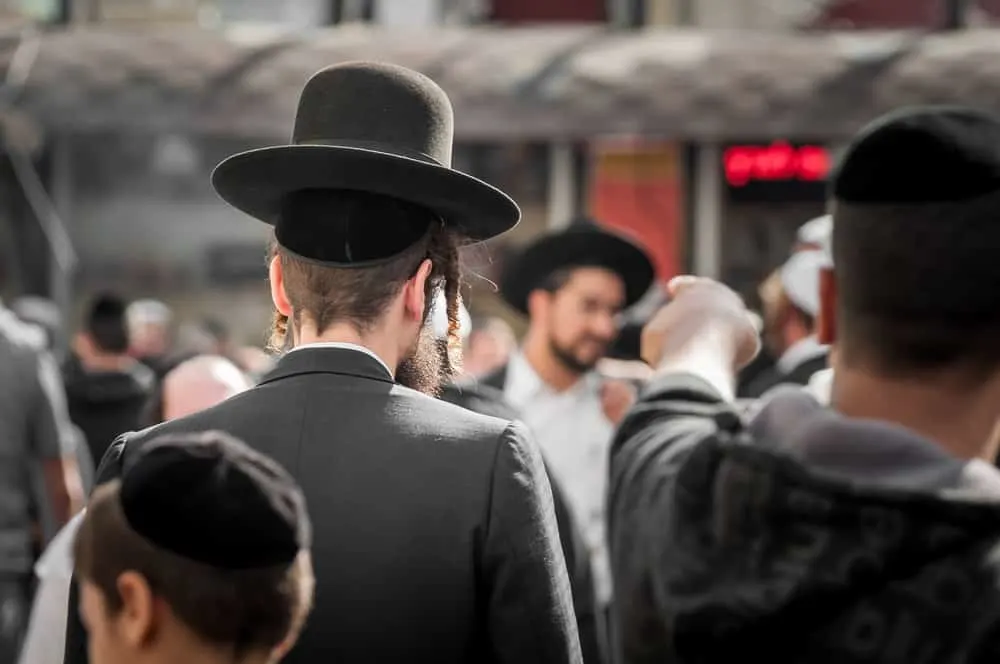 The Jewish Hasid in traditional clothes with long payos walked through a crowd with many Jewish descendants.