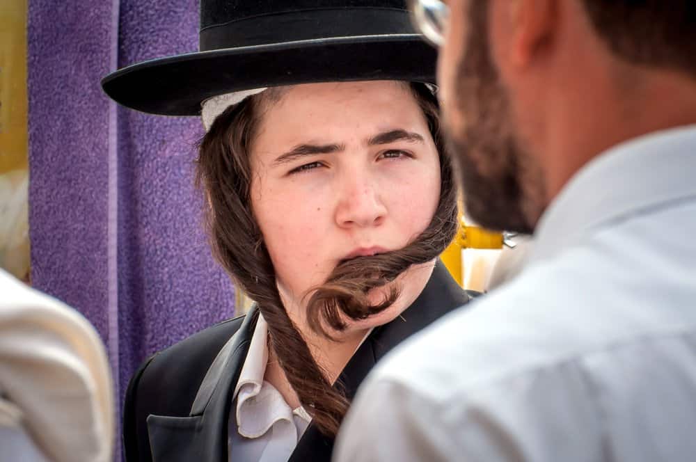 A young Hasid in a traditional Jewish hat discussed a distinct Jewish odor as racial anti-Semitism with a friend.