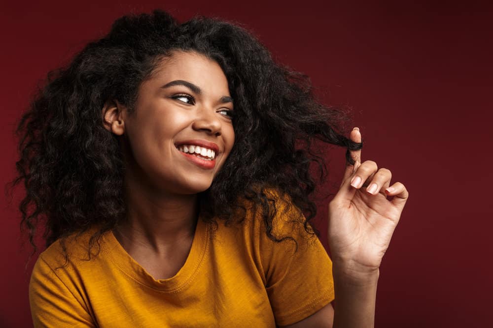 A woman with damp hair that's becoming wavy after getting wet styled with a curling iron and wide-tooth comb.