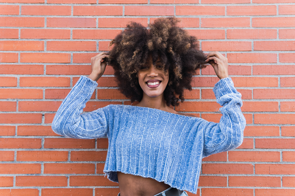 Young black woman after rinsing hair everyday with plain rice water hair treatments for less porous hair.