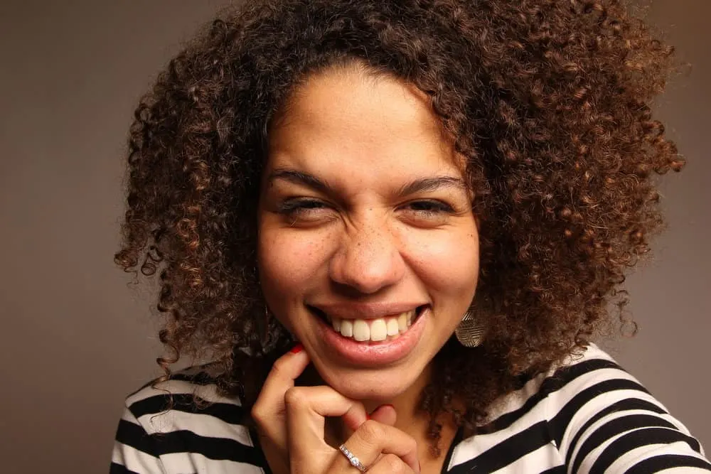 How Long Can You Keep Mixed Hair Dye? Can You Save Leftovers? 5 An African American woman with medium brown natural curls is seen sporting semi-permanent hair color on her head.