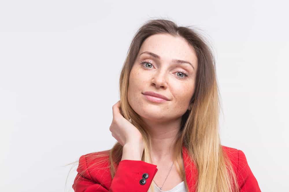 A freckled Jewish woman with beautiful eyes showing off her real hair.