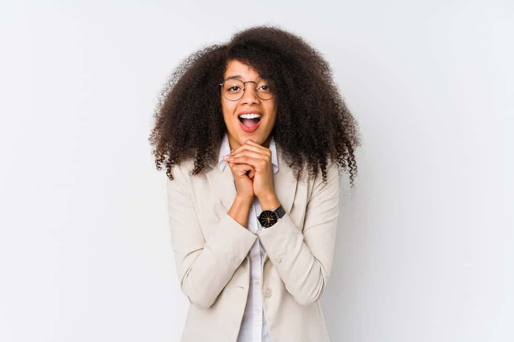 Cute young black girl with wavy hair after drying her wet hair wearing it shoulder length with a beige business suit.