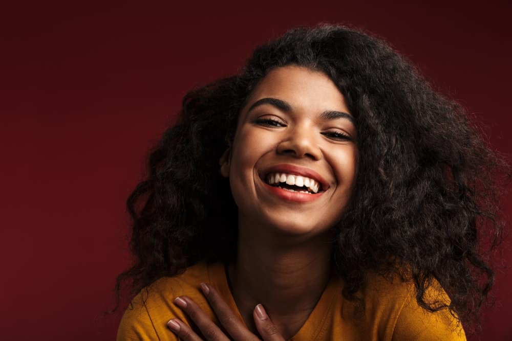 Young black girl with naturally straight hair after getting wavy hair extensions to thicken up with hair strands.