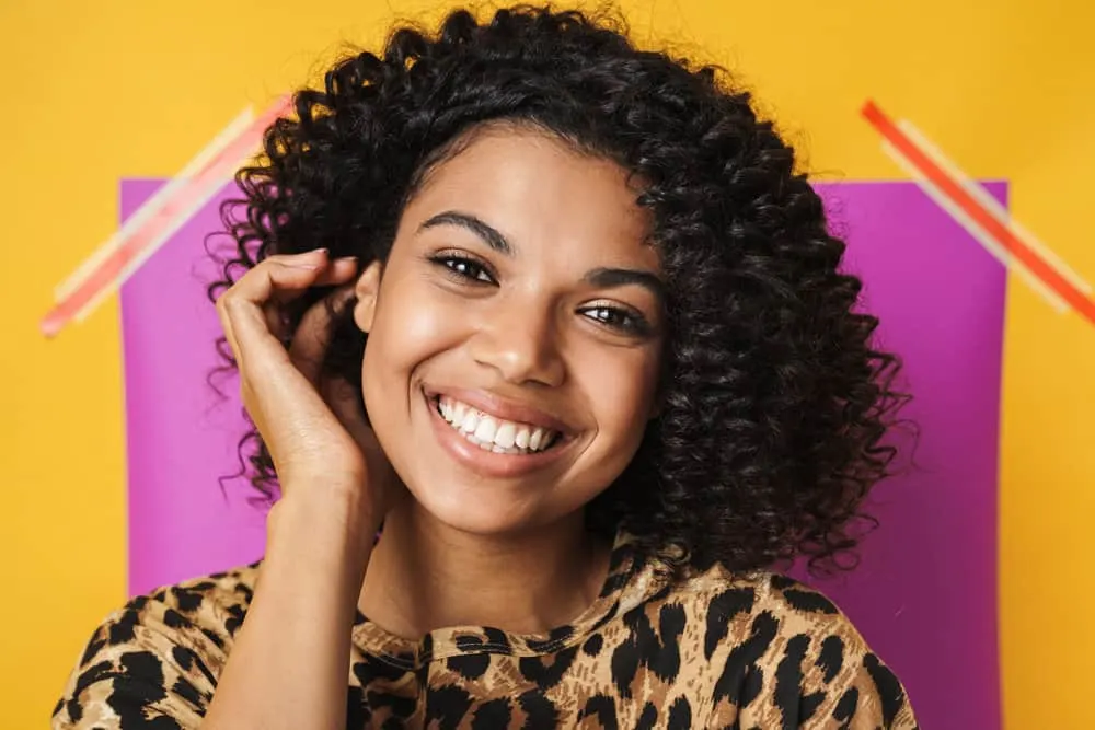 How to Get Rid of Dandruff Without Stripping Hair Color 3 A cheerful black female with brown hair and a flaky scalp that's treating dandruff with a sulfate-free shampoo.