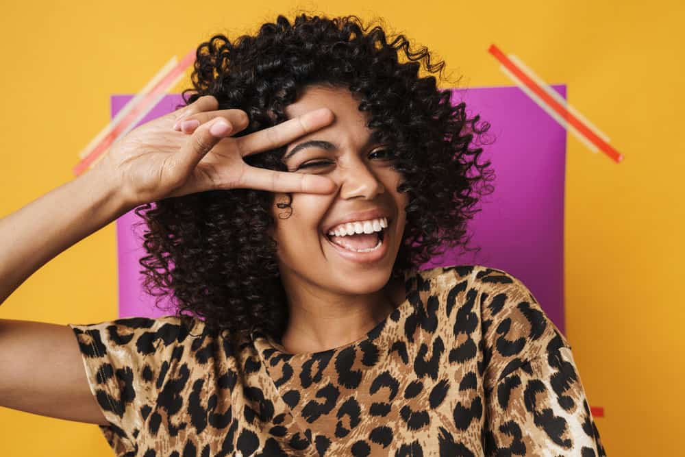 A young female having fun after styling her natural curls with olive oil, vitamin E oil, and cocoa butter.