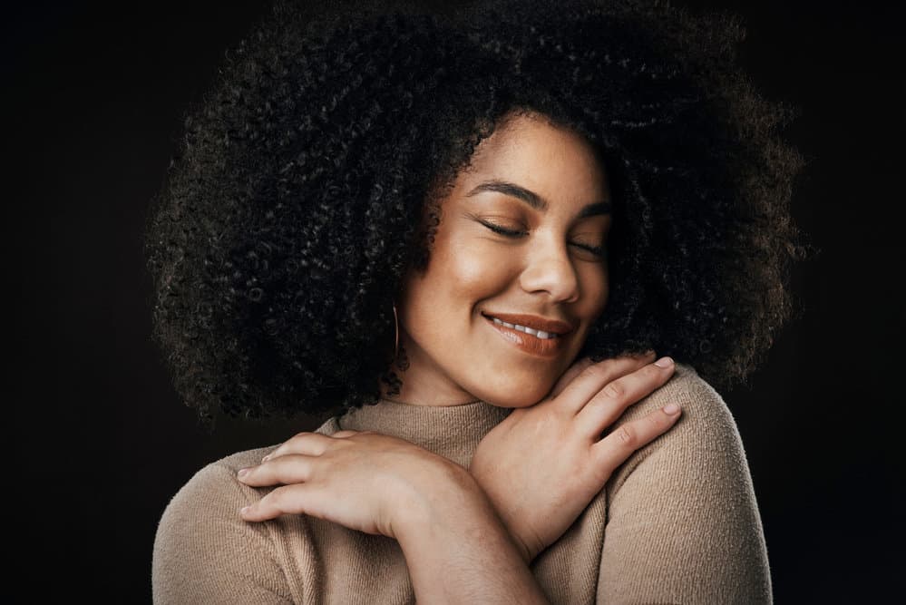 A pleasant young woman with bouncy curls coiffed with a clean hairbrush after normal cleaning.