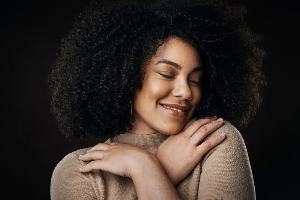 A pleasant young woman with bouncy curls coiffed with a clean hairbrush after normal cleaning.