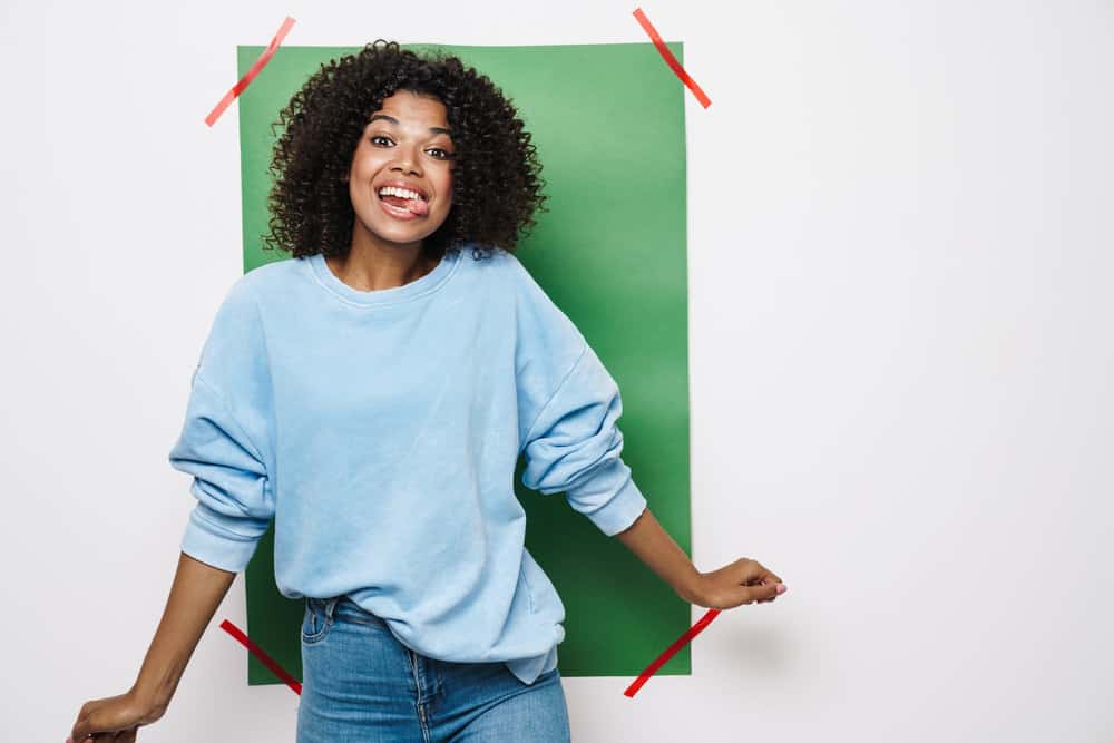 A funny black woman with shoulder-length hair growth has her natural coils styled with aloe vera gel and coconut oil.