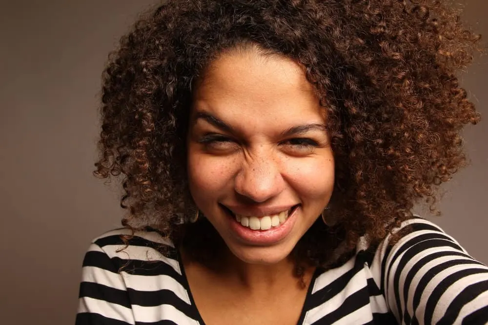 How Long Can You Keep Mixed Hair Dye? Can You Save Leftovers? 6 Light-skinned black woman with medium brown natural curls who is wearing semi-permanent hair color on her head.