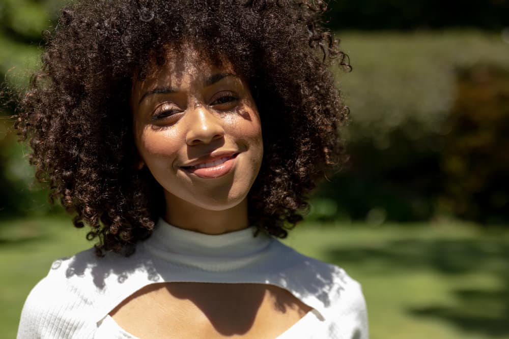 African American female with an itchy and flaky scalp has thick hair styling her hair with natural coconut oils.