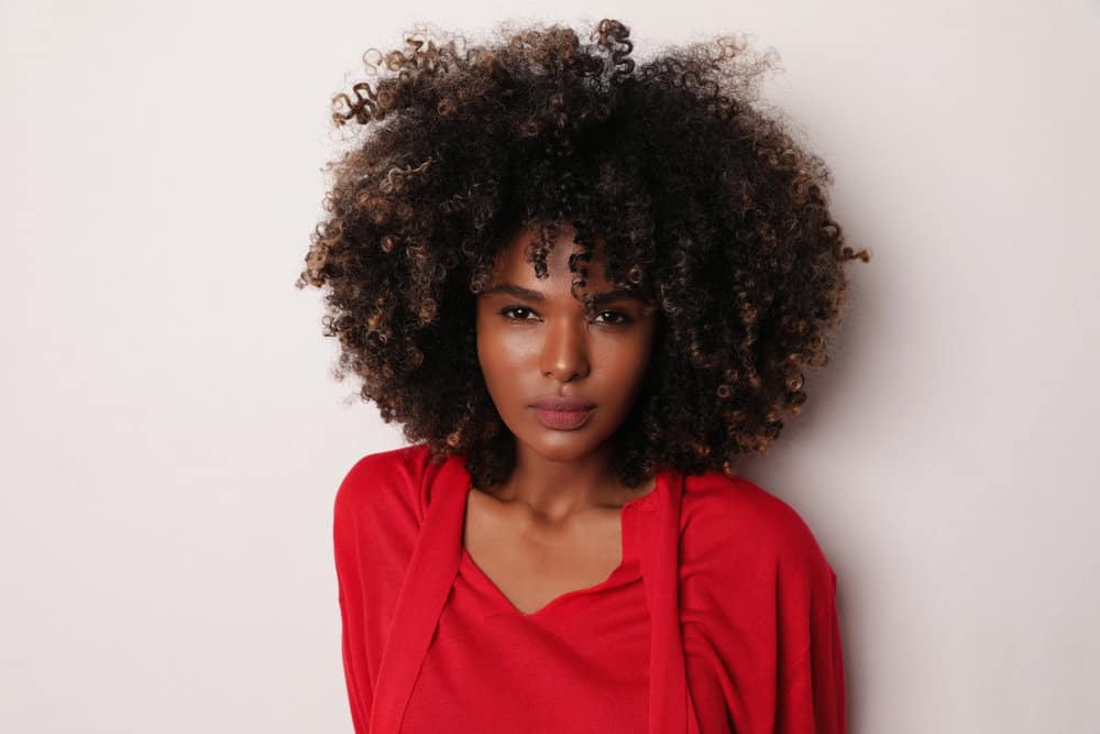 African American woman with a big curly hairdo with an amazing smell that triggers pleasure while brushing past.
