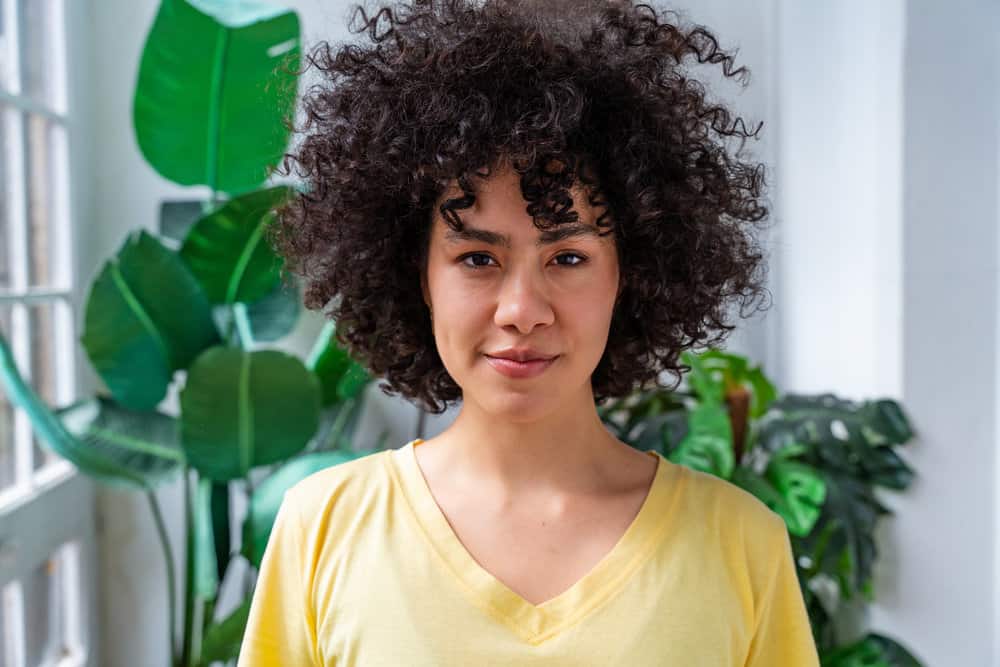 A Latino woman enjoying the nourishing hair benefits of using prepared rice water on her weak hair strands.