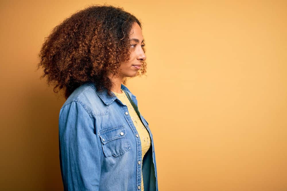 Black woman wearing a denim shirt planning to reapply color oops to remove unwanted hair dye.