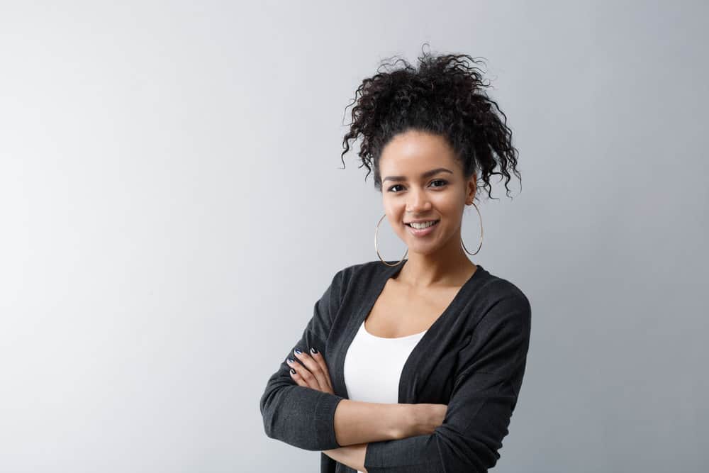 Cute African American female on her curly girl journey rocking a pineapple updo with a 3a curl pattern.