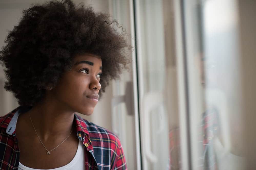 Beautiful African American woman after getting a pre-poo treatment on her dry hair with a hair mask.